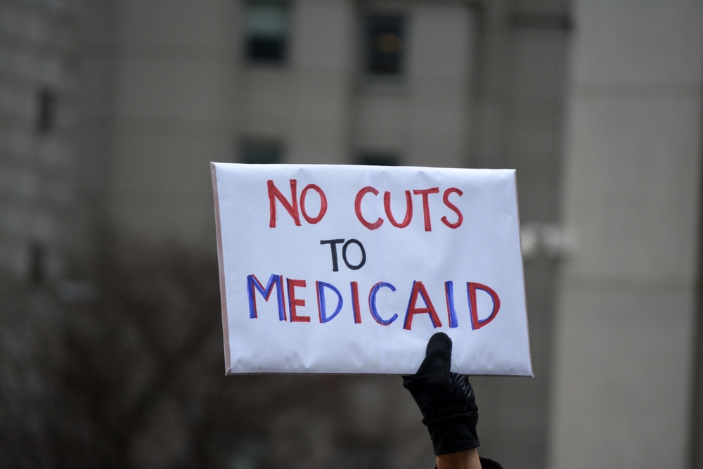 Person holding sign that says No Cuts to Medicaid.